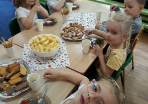 Dzieci siedzą przy stole i zjadają lody z galaretką.