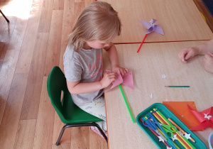dziewczynka konstruuje wiatraczek z papieru