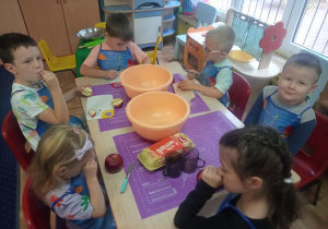 dzieci przy stolikach przygotowują owocowe ciasta