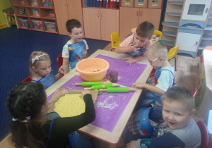 dzieci przy stolikach przygotowują owocowe ciasta