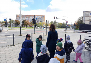Dzieci przyglądają się ruchowi ulicznemu na skrzyżowaniu.