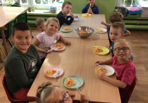 Dzieci jedzą samodzielnie przygotowaną surówkę z kiszonej kapusty i marchewki.
