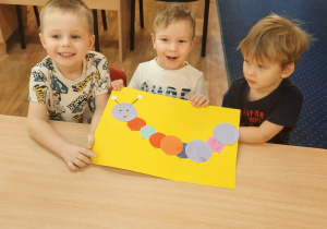 Trzej chłopcy prezentują pracę wykonaną z kół.