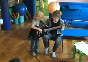 Chłopiec próbuje grać na gitarze elektrycznej.